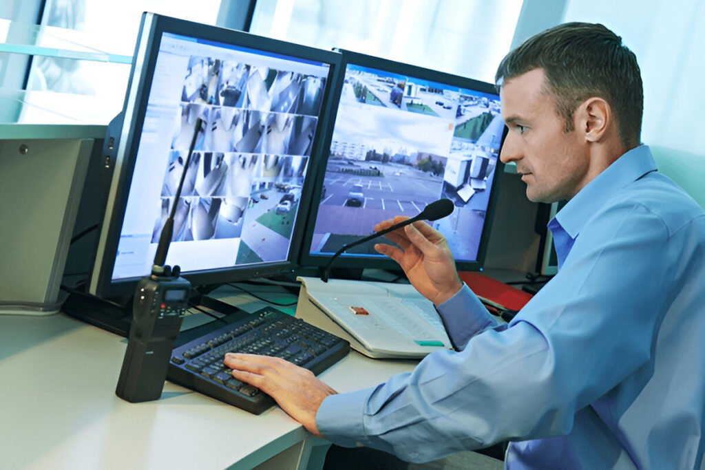 Security worker monitoring live video surveillance footage for real-time threat detection and safety enforcement.